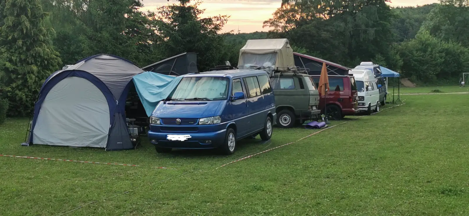 Blaue Bullis und Campingzelte auf der Zeltwiese