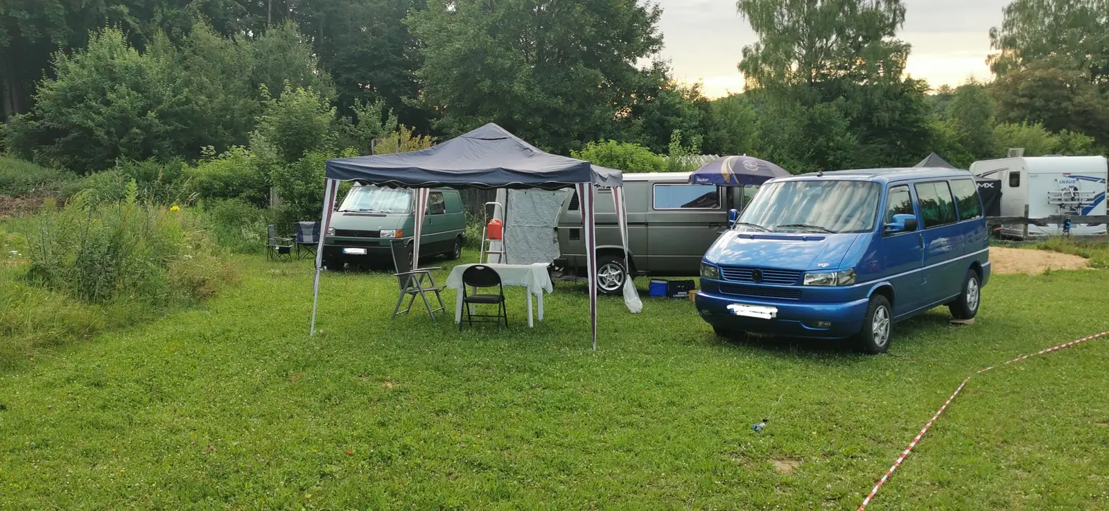 Ein klassischer grün-cremefarbener Bulli zwischen Campern